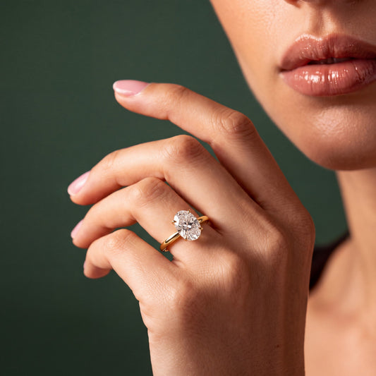Aurora solitaire forlovelsesring med oval diamant i gult gull, båret på hånd