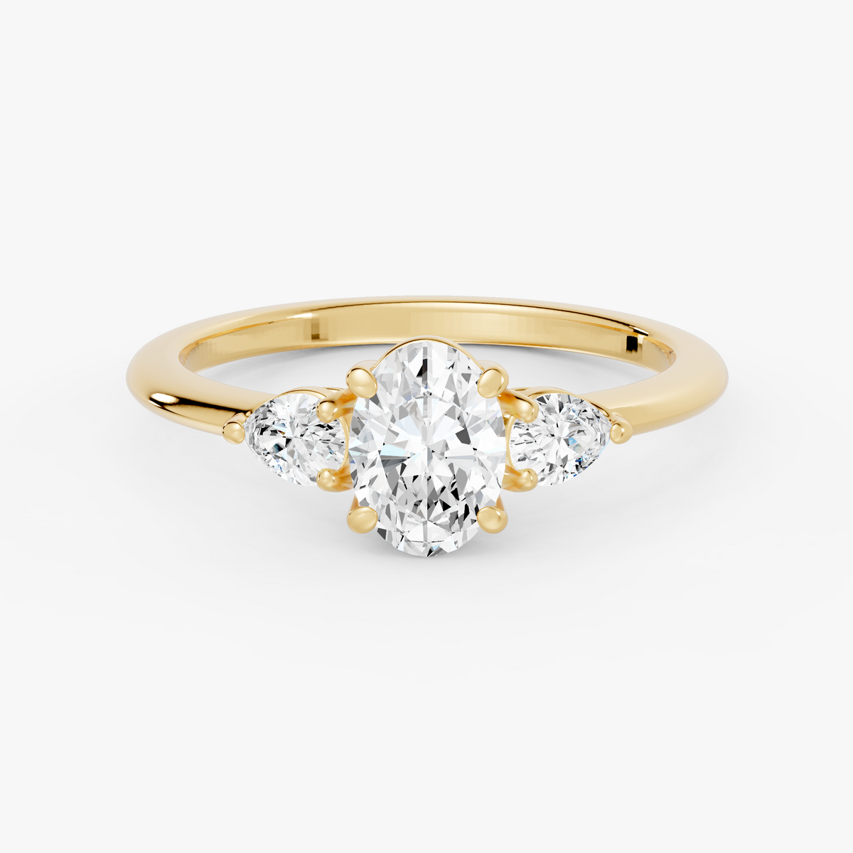 Delphine trestens forlovelsesring med oval diamant og to pæreformede sidesteiner i gult gull, liggende sett forfra