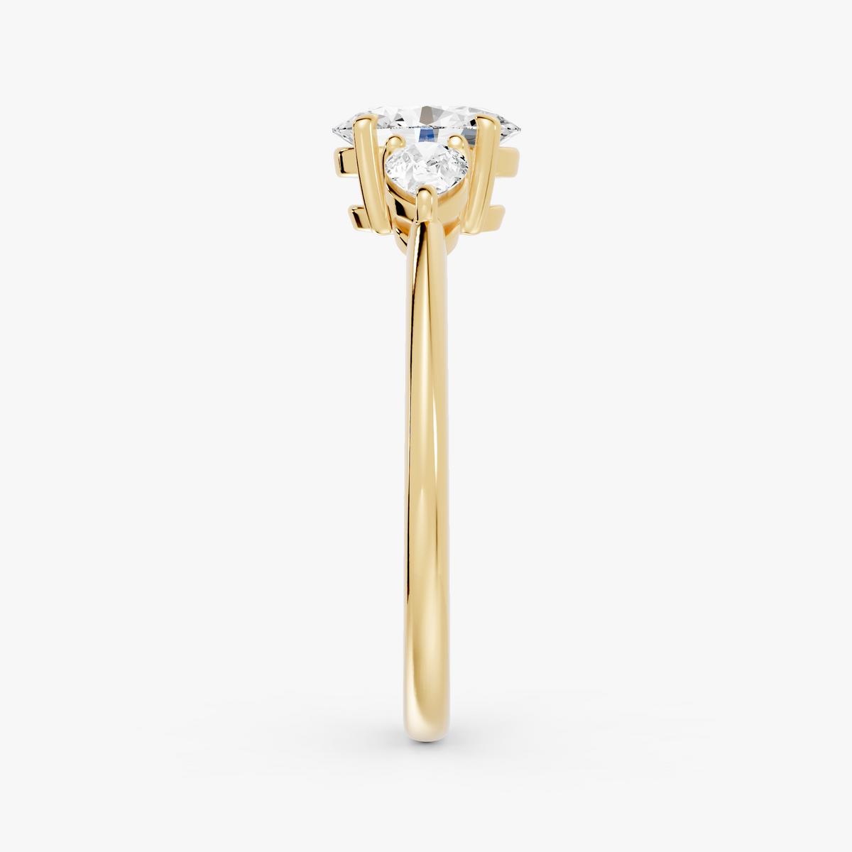 Delphine trestens forlovelsesring med oval diamant og to pæreformede sidesteiner i gult gull, fra siden