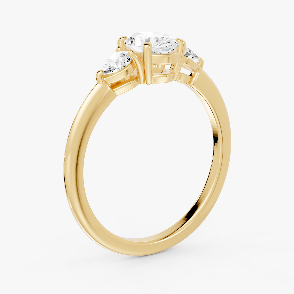 Delphine trestens forlovelsesring med oval diamant og to pæreformede sidesteiner i gult gull, skrått fra siden