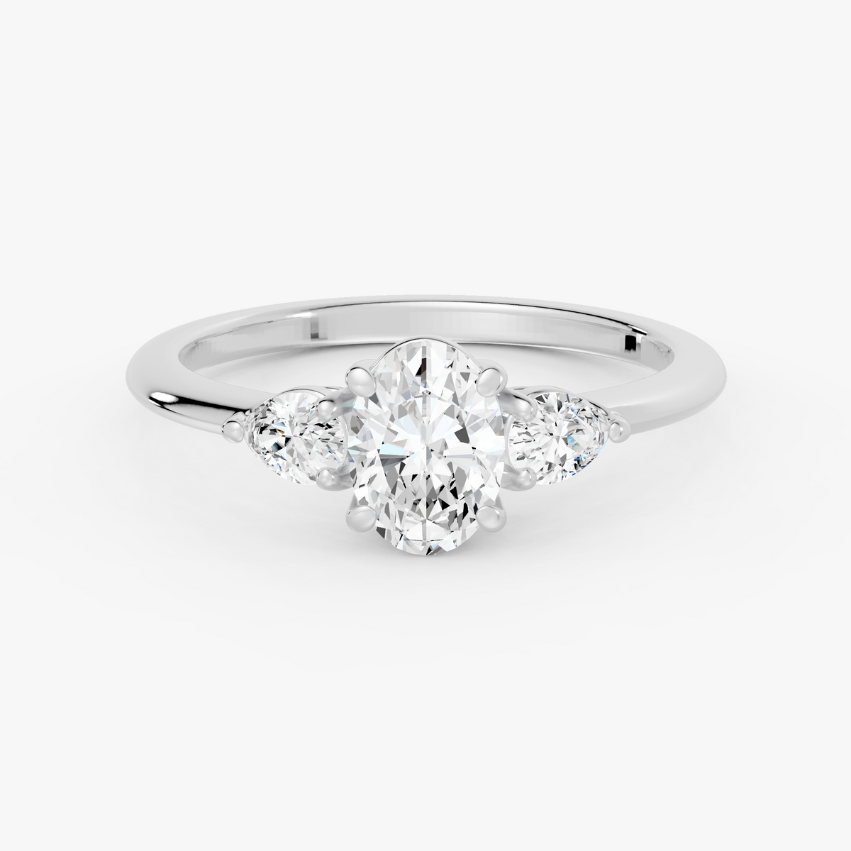 Delphine trestens forlovelsesring med oval diamant og to pæreformede sidesteiner i hvitt gull, liggende sett forfra