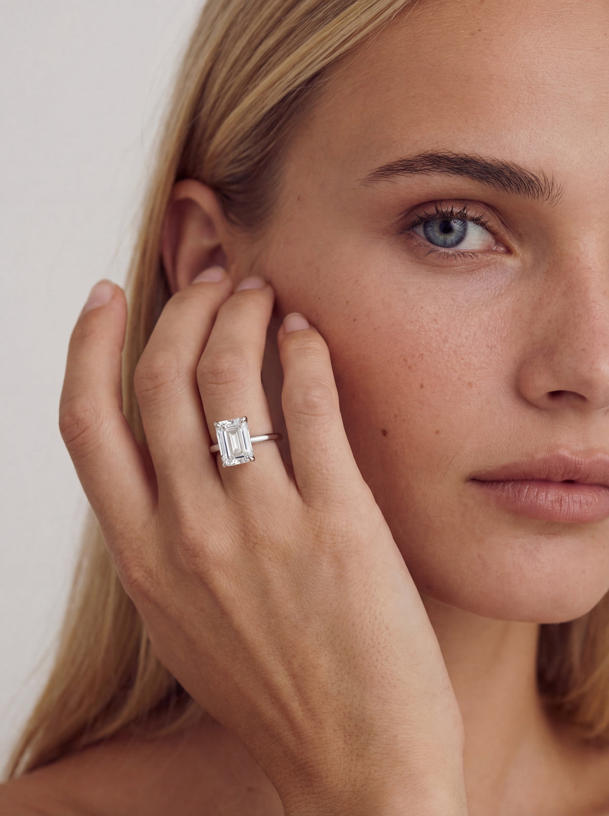 Elara solitaire forlovelsesring med emerald cut diamant i hvitt gull båret på modell